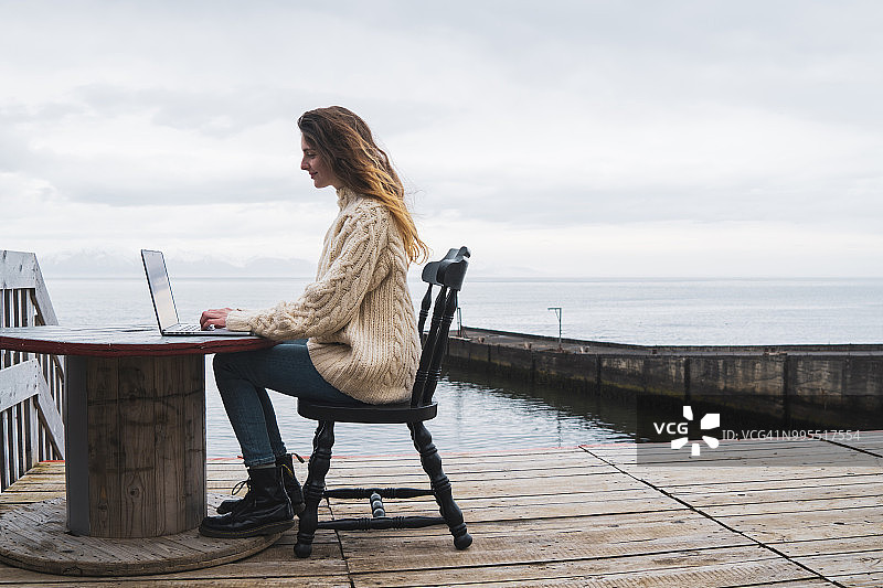 冰岛，一个在海边用笔记本电脑的女人图片素材