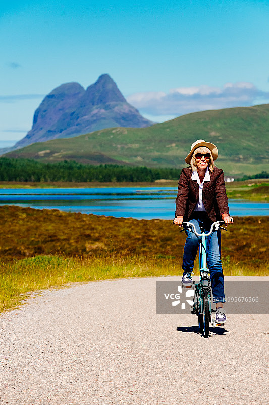 在苏格兰骑折叠自行车的资深女性图片素材
