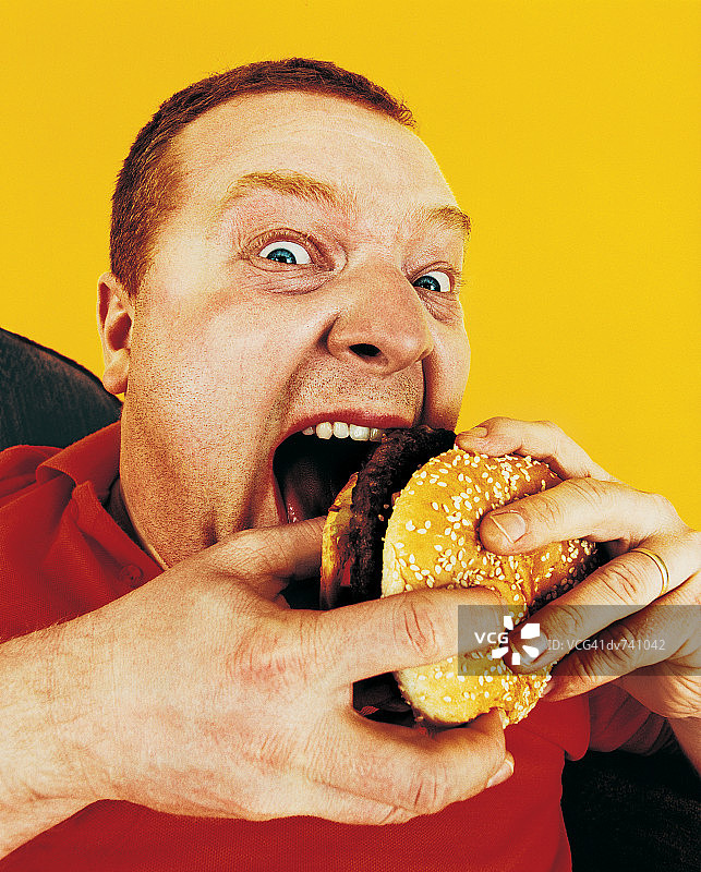 一个饥饿的人吃汉堡包的肖像图片素材