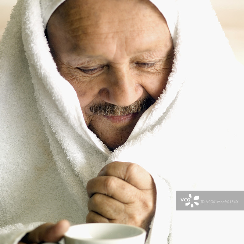 高级男子用毛巾裹着头，拿着一个咖啡杯，特写图片素材