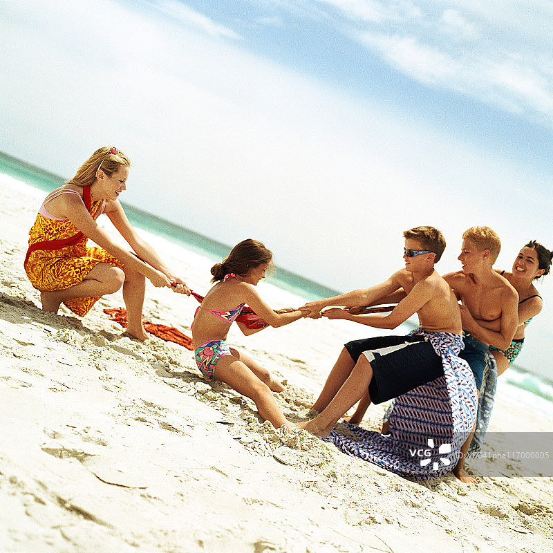 一群人在海滩上玩拔河游戏图片素材