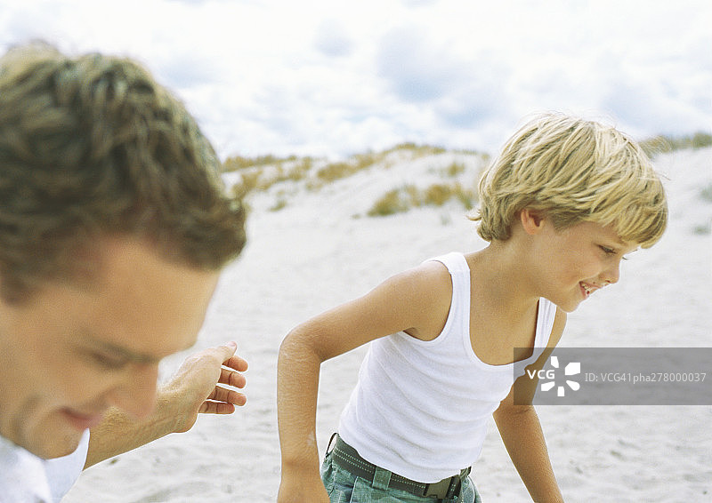 男孩和父亲在海滩上跑步图片素材