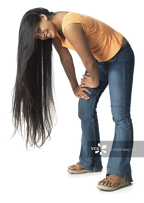 一个穿着牛仔裤和橙色衬衫的少数民族少女倾身过来，挥舞着她的手图片素材
