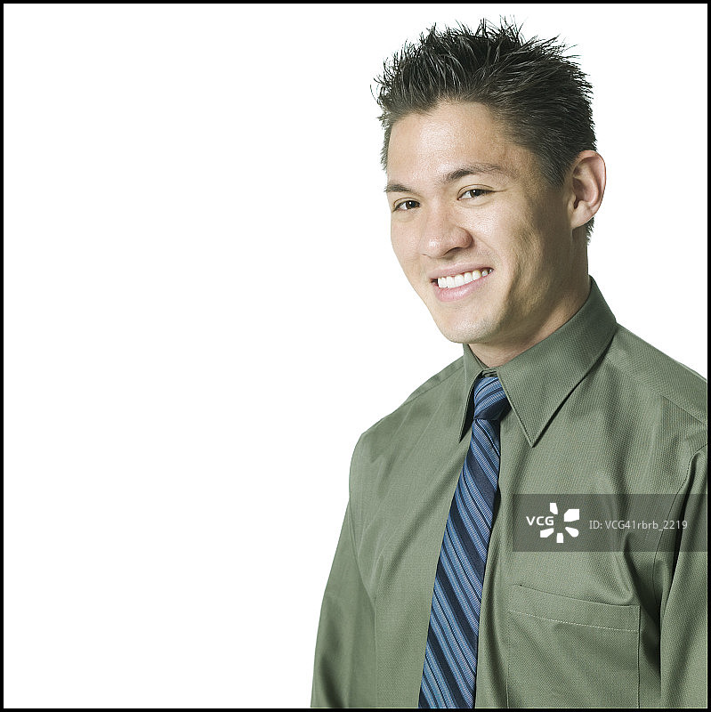 一个年轻的成年男子的肖像，穿着绿色衬衫和领带，他对着镜头咧嘴笑图片素材