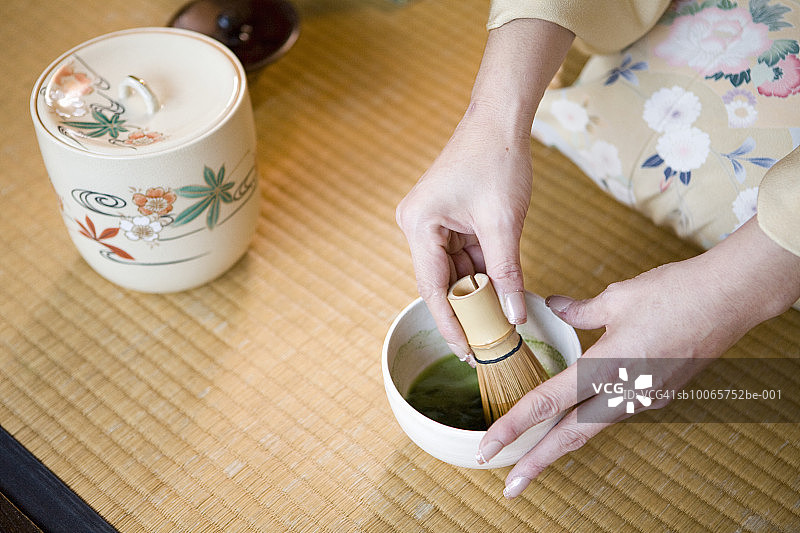 妇女用搅拌器搅拌绿茶，双手合上图片素材