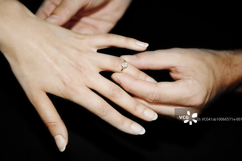 男人把钻石戒指戴在女人的手指上图片素材