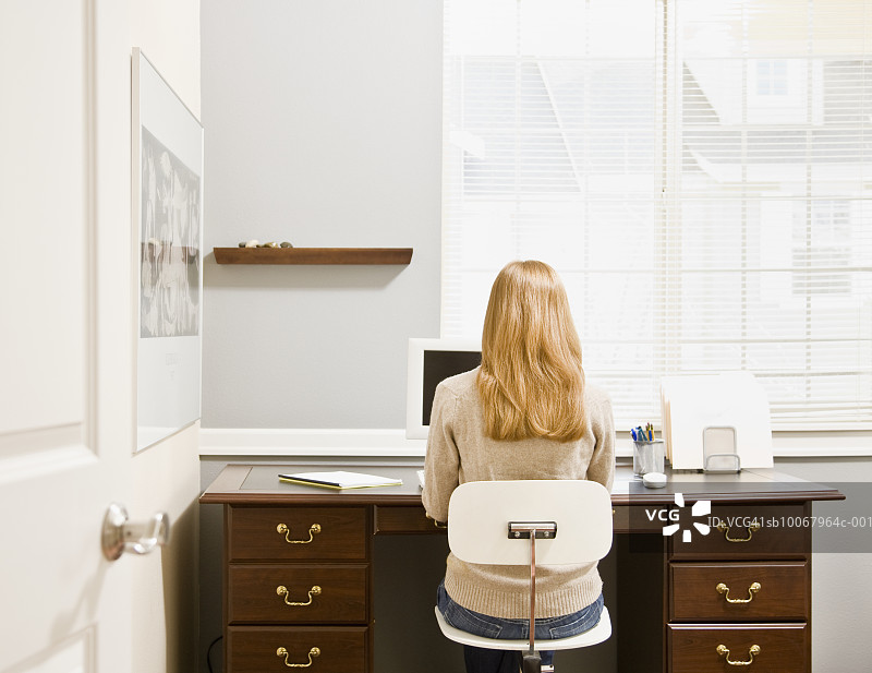 女人坐在办公桌前，用着电脑，后视镜图片素材