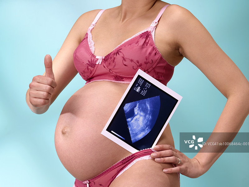 孕妇拿着超声图像，显示大拇指向上的标志，中段图片素材