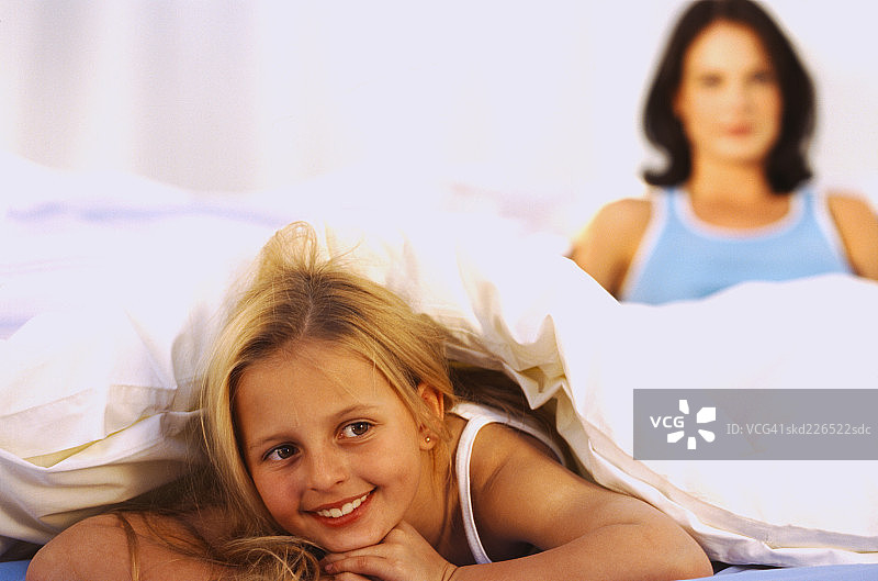 一个年轻女孩的特写(6-8)躺在床上和她的母亲图片素材
