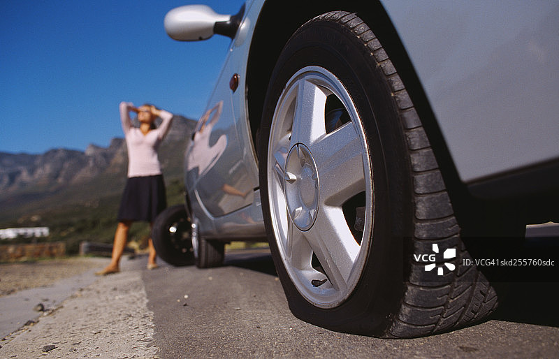 一个年轻女子站在汽车前的低角度视图图片素材