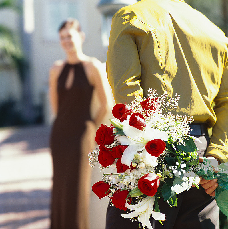 一个男人背后为一个女人捧着一束玫瑰的背影图片素材