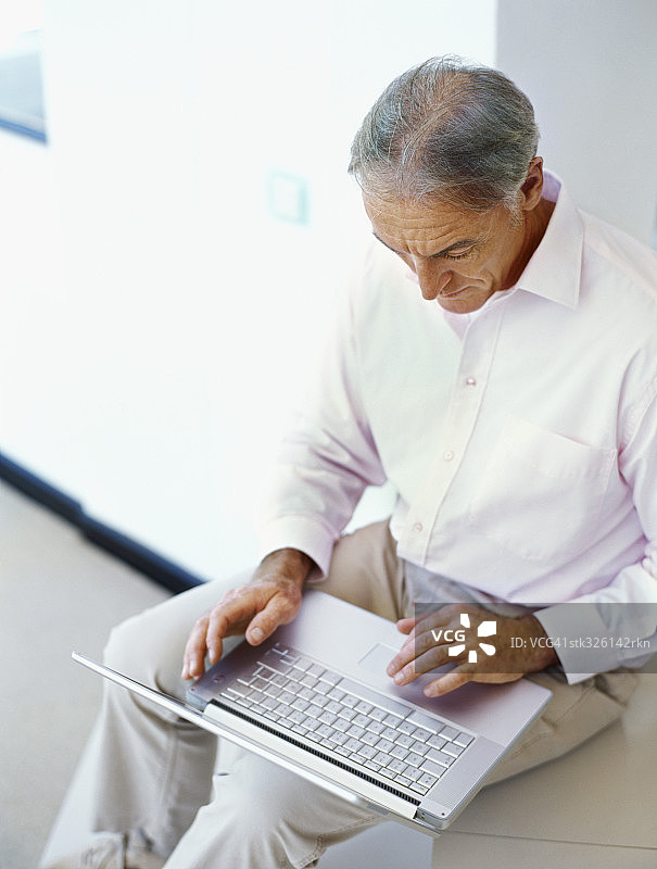 一个成熟男人使用笔记本电脑的高角度视图图片素材