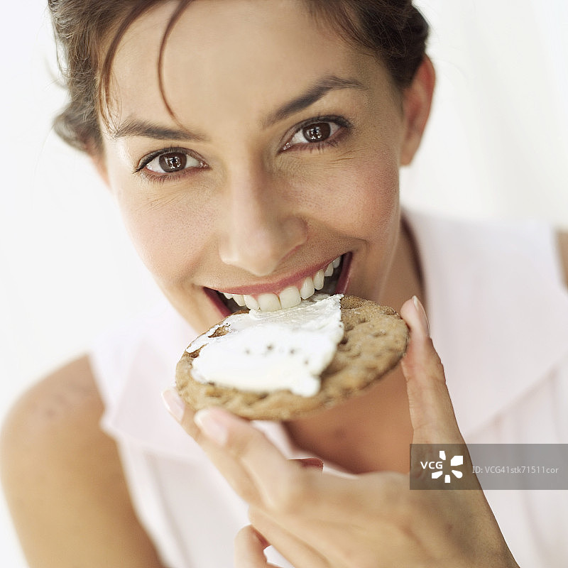 女人微笑着咬着奶酪饼干的肖像图片素材