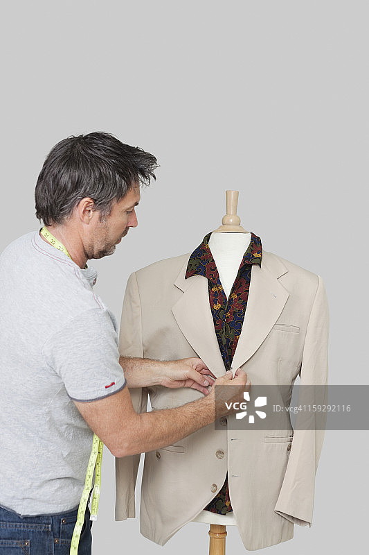 男裁缝调整西装在裁缝的假人在彩色的背景图片素材