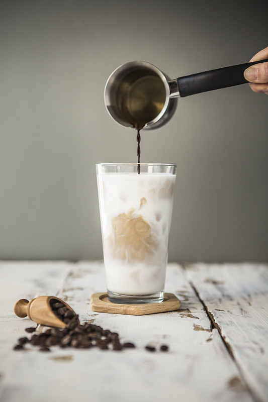 在冰牛奶中倒咖啡的特写图片下载
