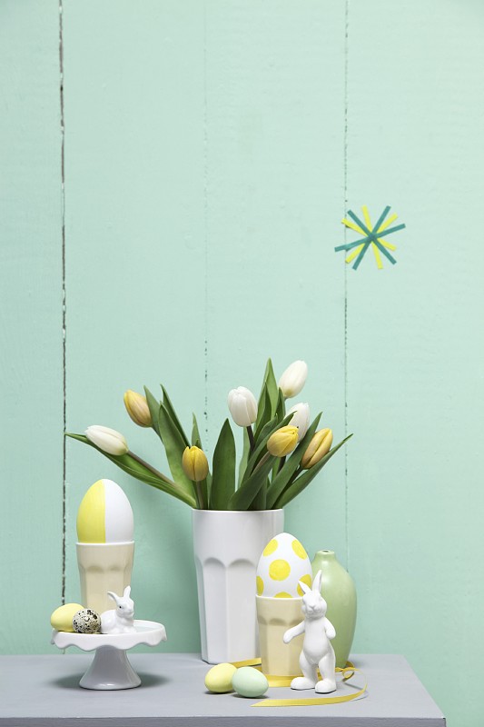 柔和的复活节安排;郁金香在陶瓷烧杯，鸡蛋和兔子饰品图片下载