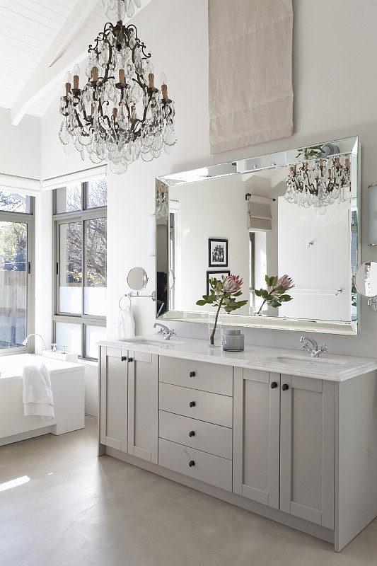 浅灰色浴室盥洗台下优雅的镜子，吊灯和高高的，白色的屋顶结构图片下载
