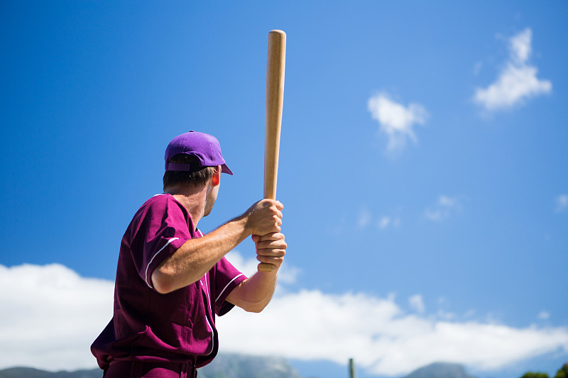 低角度的棒球运动员拿着球棒对着晴天的蓝天图片下载