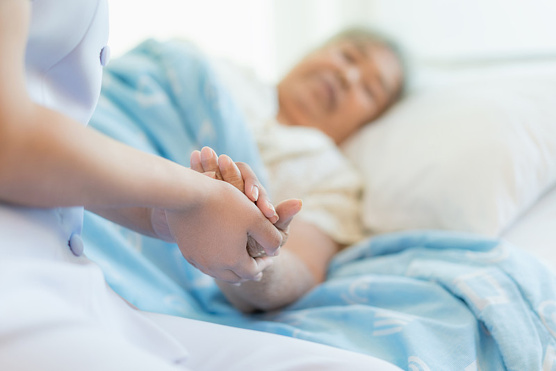 护士坐在病床上，旁边是一位老妇人在帮忙图片下载