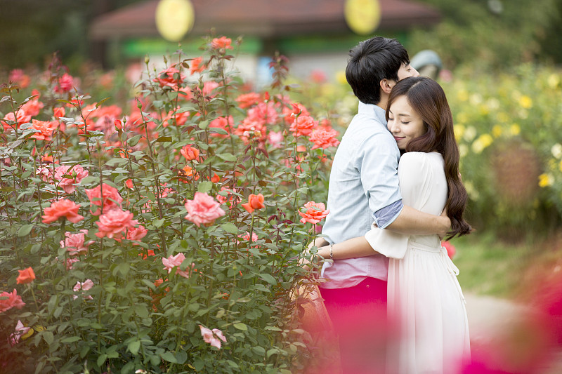 一对情侣站在植物园的花坛上相拥的照片摄影图片下载