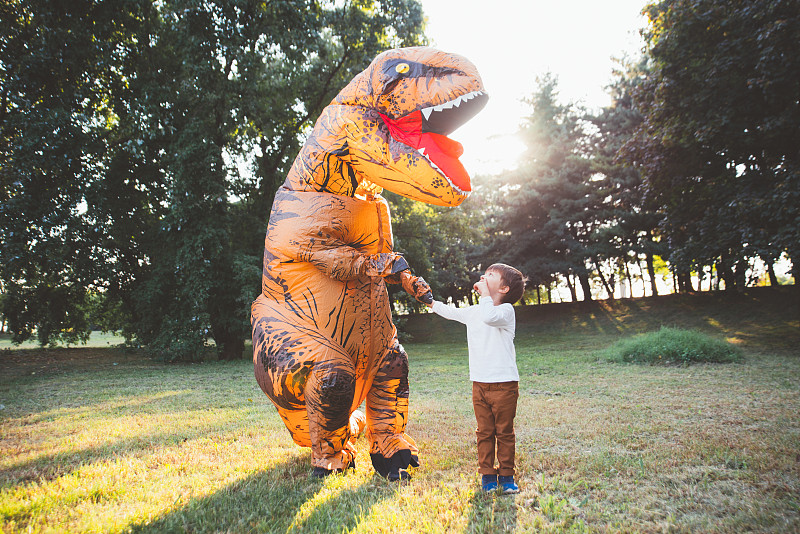爸爸和儿子在公园里玩，穿着恐龙服装图片下载