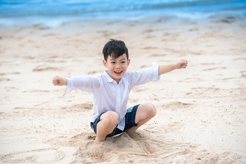 快乐的亚洲男孩在夏天的海滩上玩图片下载