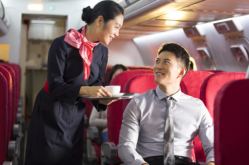 青年女乘务员在飞机机舱里给青年男商务人士咖啡图片下载