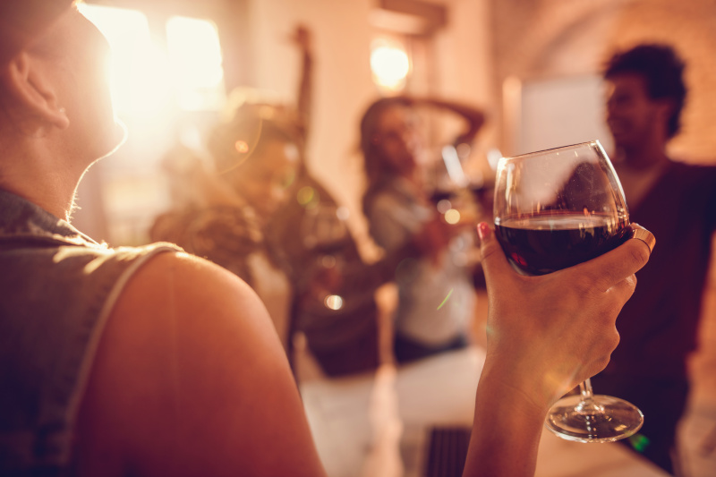 近距离的女人享受在办公室派对的葡萄酒。图片下载