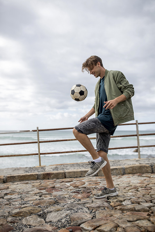 快乐的年轻人在海边平衡足球图片下载
