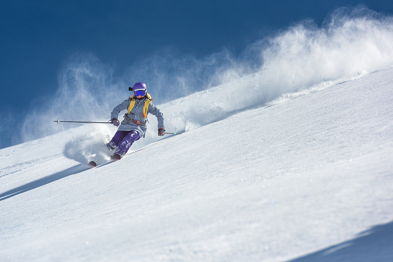 女滑雪者在新鲜的粉状雪上雕刻图片下载