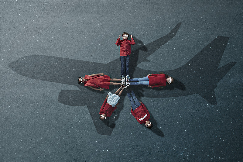 一群穿着红色衣服的孩子躺在油漆飞机上，戴着3d眼镜图片素材