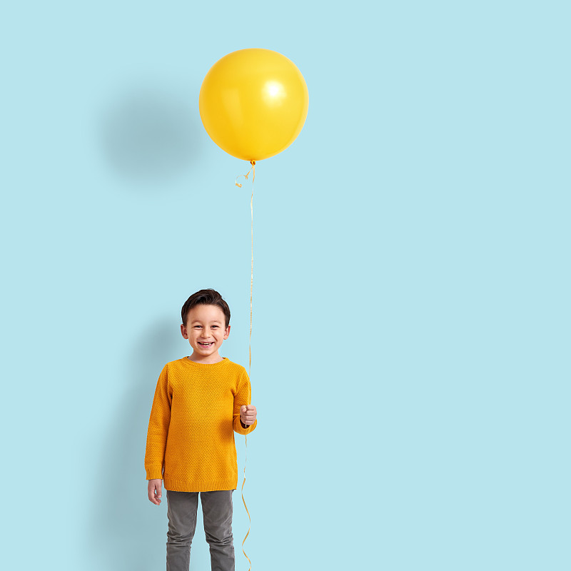 可爱的孩子拿着一个黄色的气球图片下载