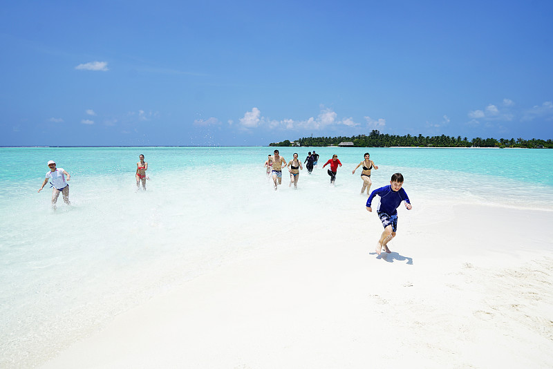 美丽的年轻人，中年和老年人有乐趣跑出浅水在沙岛海滩4月，马尔代夫图片下载