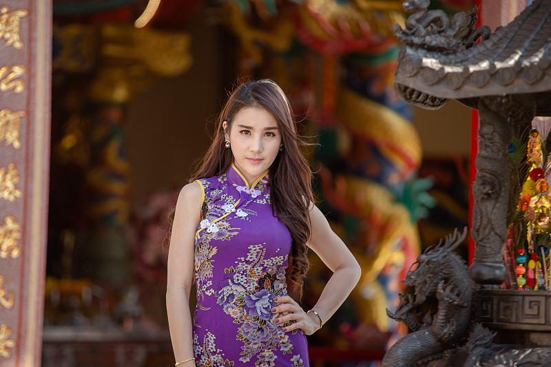 中国妇女穿着传统旗袍站在中国寺庙。图片素材