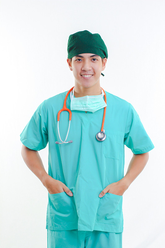 微笑医生的肖像与手在口袋站在白色的背景图片素材