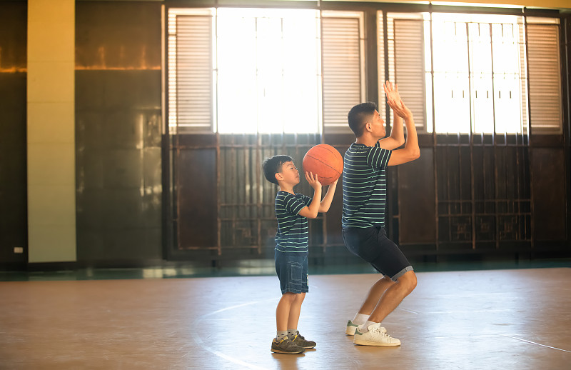 父亲和儿子在球场上打篮球的侧视图图片素材