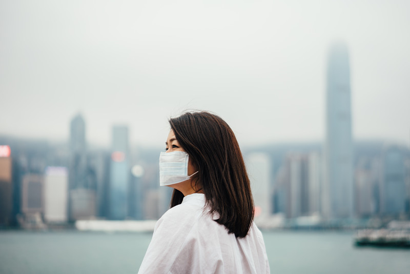 由于空气污染，年轻的亚洲妇女在城市里戴着防护口罩图片下载