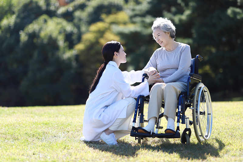 医生协助年长妇女在轮椅上图片下载