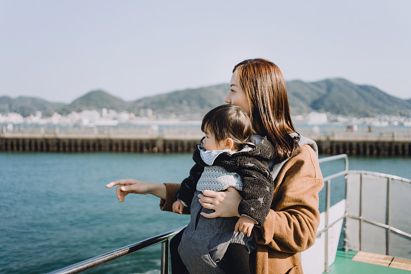 年轻的亚洲母亲和可爱的小女儿享受游艇和望向美丽的风景和海景在一个可爱的阳光灿烂的日子图片素材