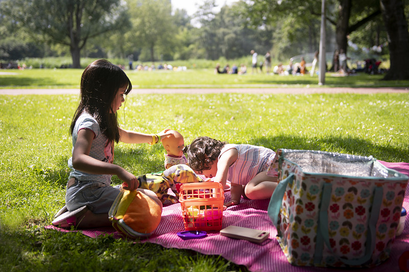 两个女孩在公园的野餐毯上图片素材