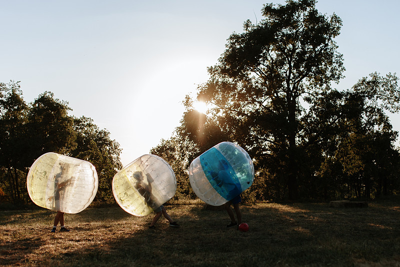 朋友们在晴朗的天空下的公园里玩泡泡足球图片素材