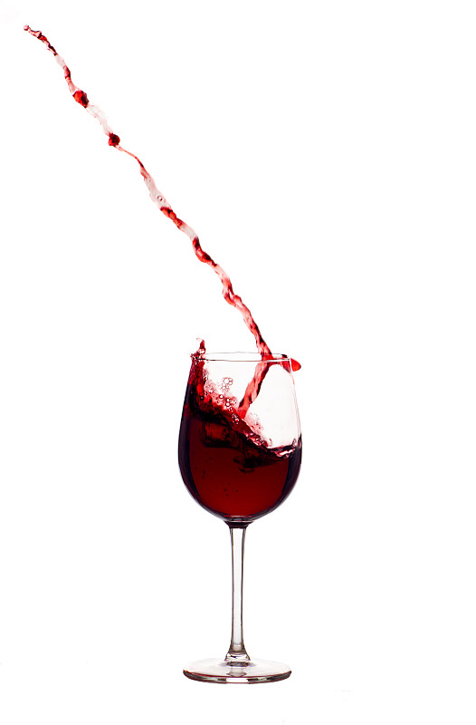 在白色背景下，红酒在玻璃杯中飞溅图片下载