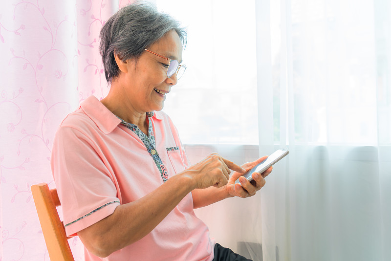 亚洲资深女性在家居客厅使用智能手机新生活技术。图片下载