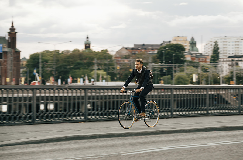 商人骑着自行车在城市街道上的天空图片素材