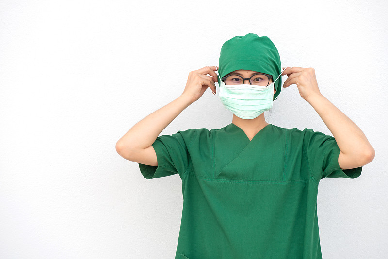 年轻亚洲护士身穿外科医生制服，佩戴外科口罩，以防止吸入空气中的细菌或病毒疾病。图片素材