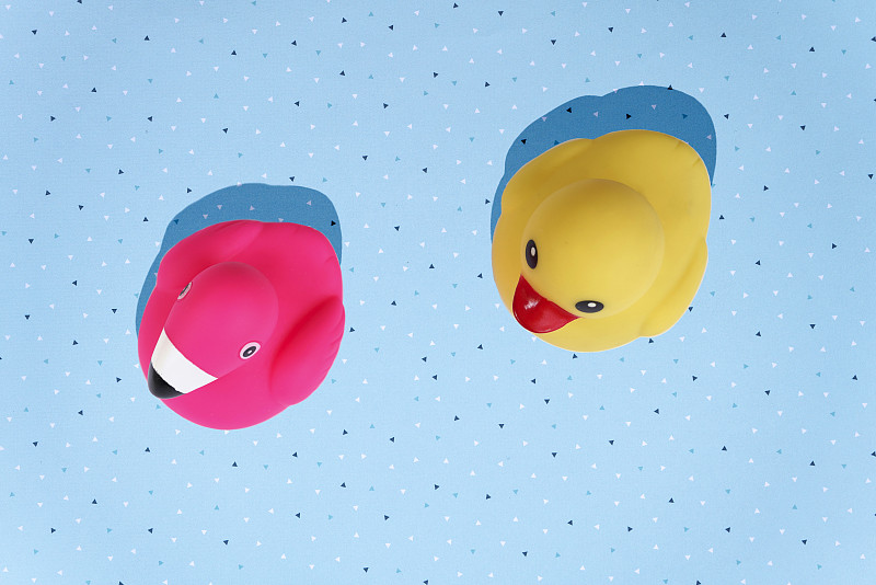 黄色的鸭子和粉红色的火烈鸟，浴室玩具在蓝色的背景与复制空间图片下载