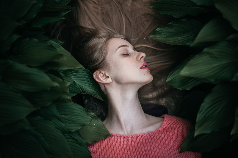 一个躺在绿叶上的女人的肖像图片素材