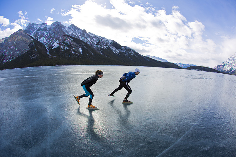 在加拿大阿尔伯塔省班夫国家公园的明尼万卡湖上，一名男子带领一名女子进行冬季速滑探险。图片下载
