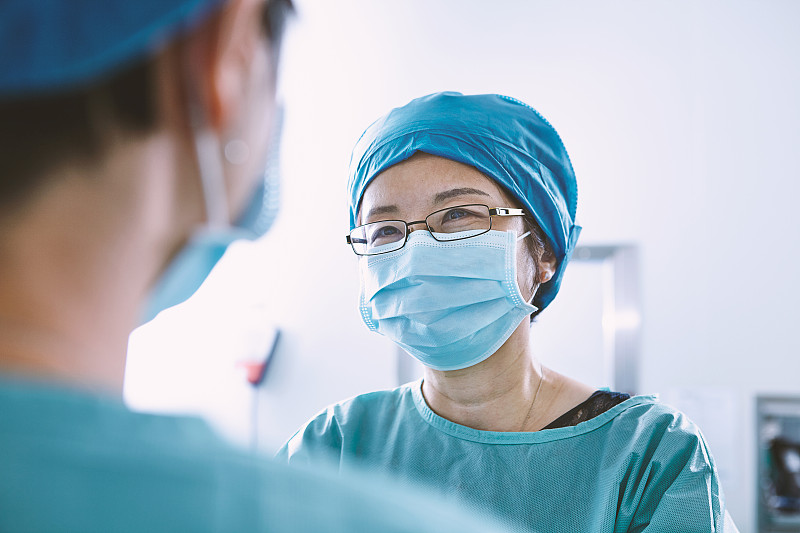 从肩膀上看，手术团队穿着手术服正在产科病房手术室讨论图片下载