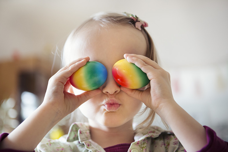 孩子拿着彩色的鸡蛋遮住眼睛图片素材